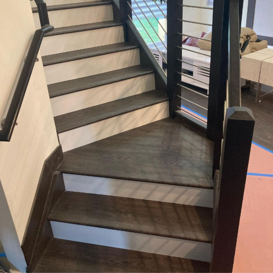 Dark wood-look stair treads and landing with a modern metal railing