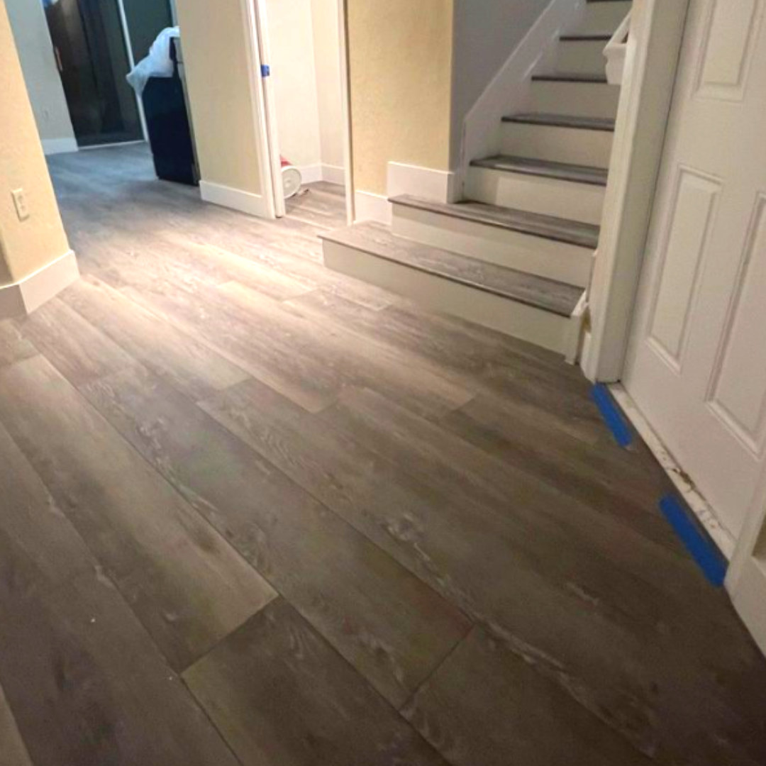 Grey wood-look flooring flowing into a hallway and staircase