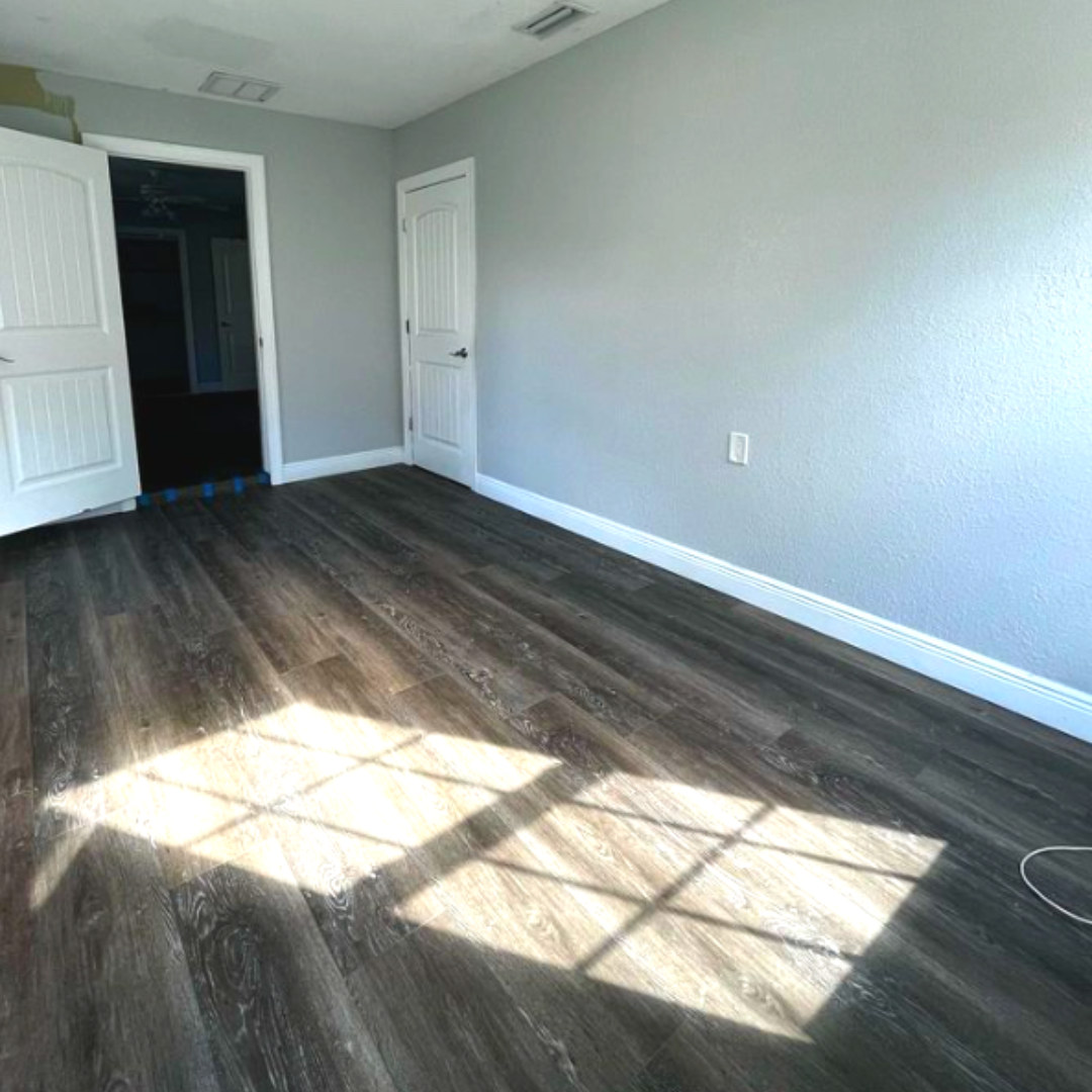 Dark vinyl plank bedroom floor with afternoon light across the planks