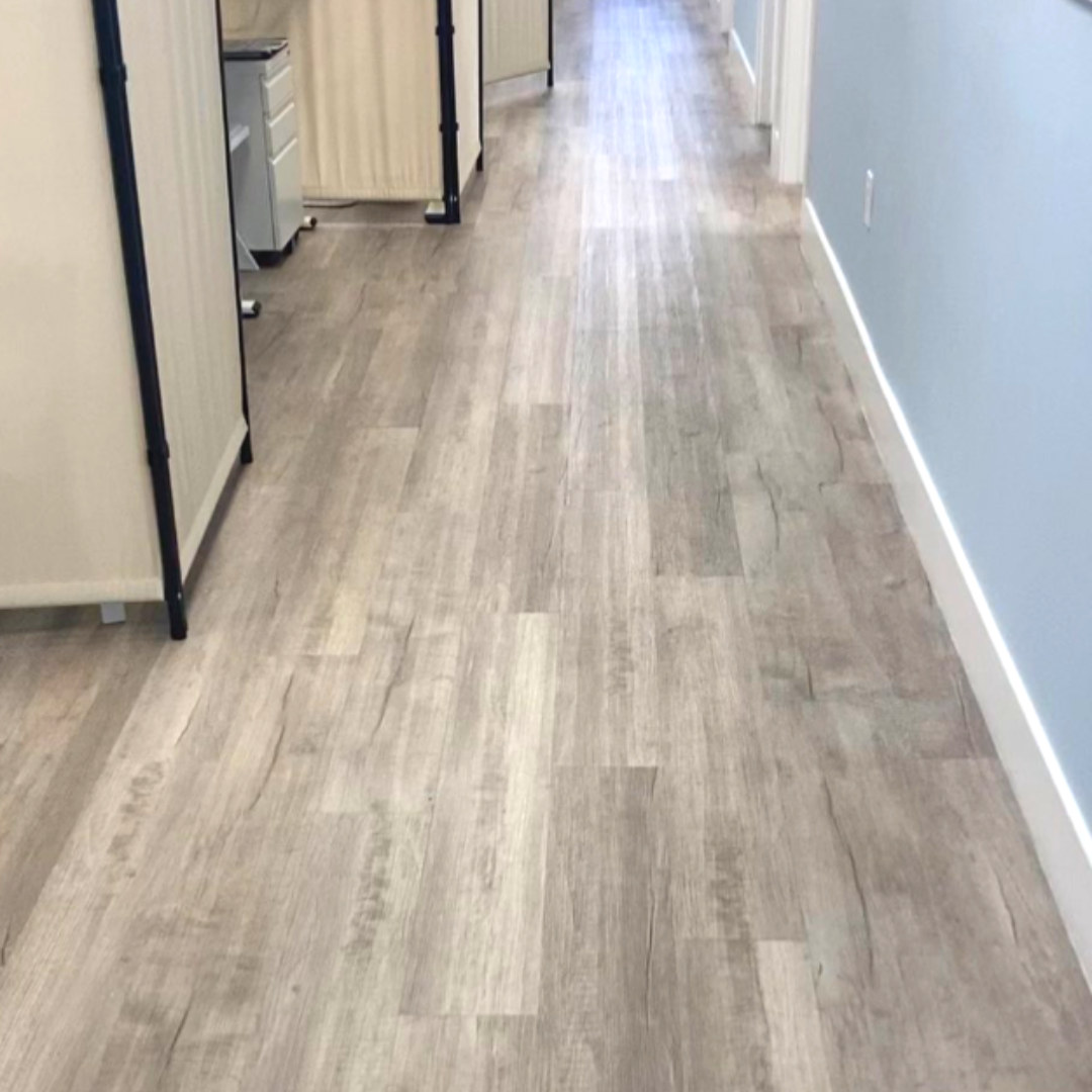 Grey wood-look flooring running down a long office hallway